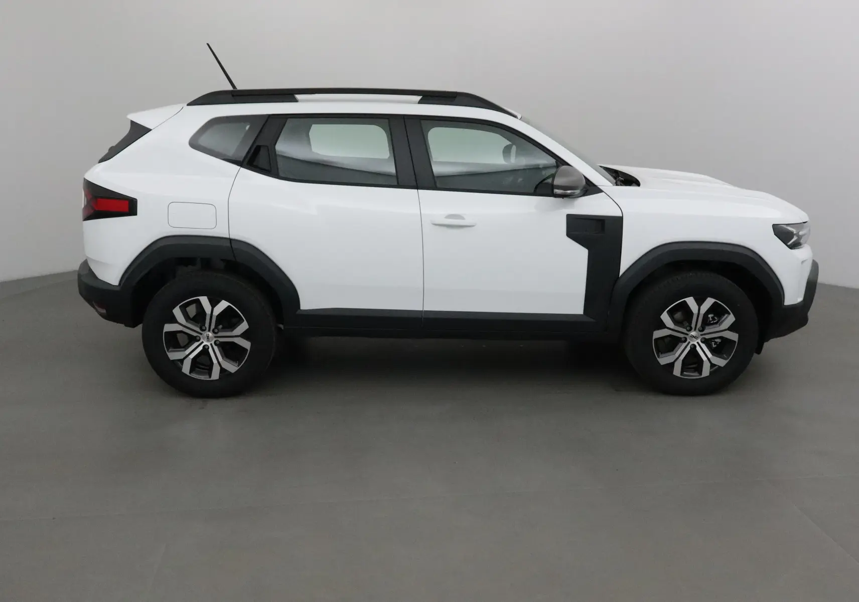 Profil côté gauche du Dacia Duster blanc glacier 2025 avec jantes alliage 17 pouces et protections noires contrastées.