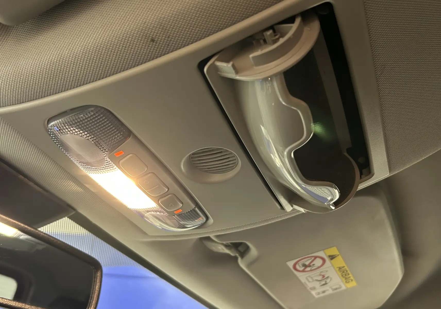 Plafonnier intérieur allumé avec rangement lunettes ouvert sur Ford EcoSport gris, vue du toit vers l'avant côté conducteur.