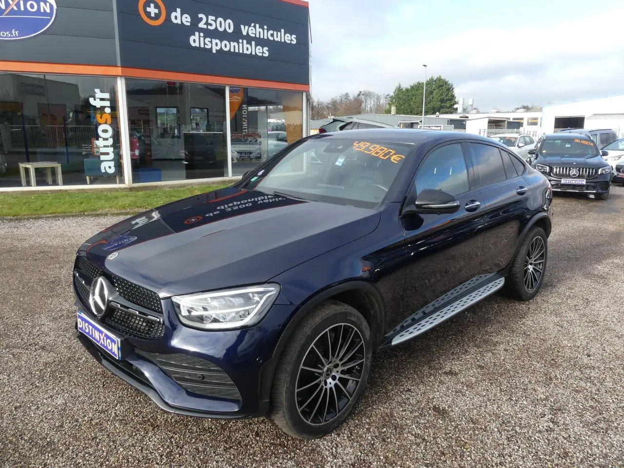 Mercedes GLC Coupé 300 hybride bleu foncé en 3/4 avant droit avec jantes AMG et marchepieds acier.