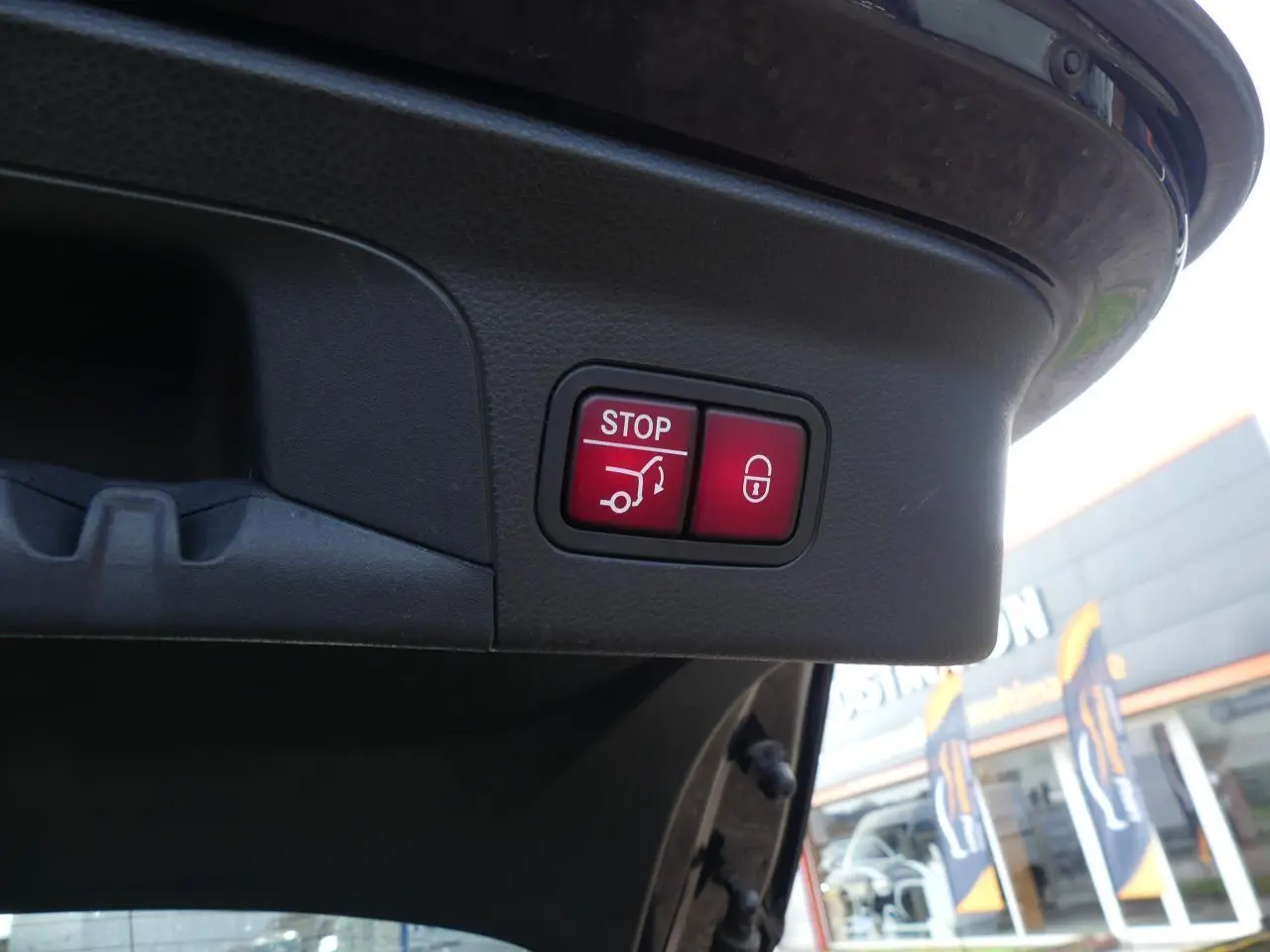 Gros plan sur les boutons rouges de fermeture et verrouillage électrique du hayon d’un Mercedes GLC Coupé bleu foncé.