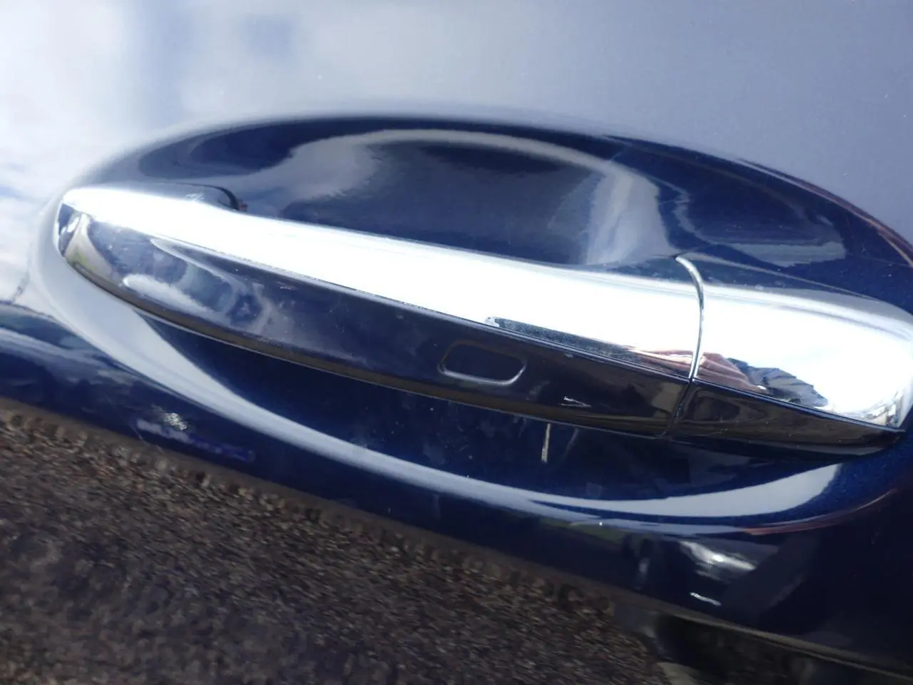 Poignée de porte chromée sur la portière côté droit d'une Mercedes GLC Coupé 300 hybride bleu foncé.