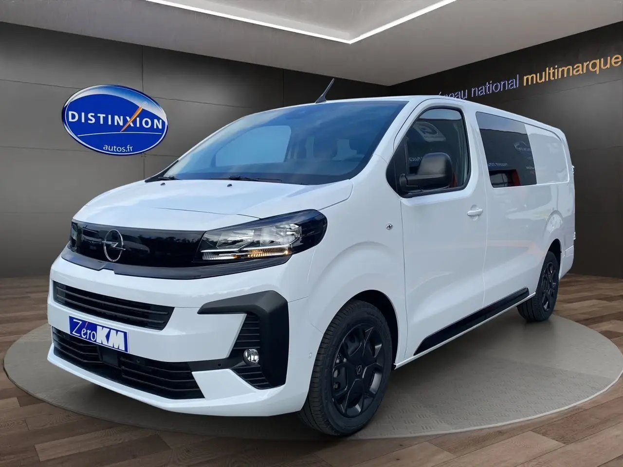 Opel Vivaro blanc en 3/4 avant droit avec jantes noires et calandre noire brillante dans un showroom.