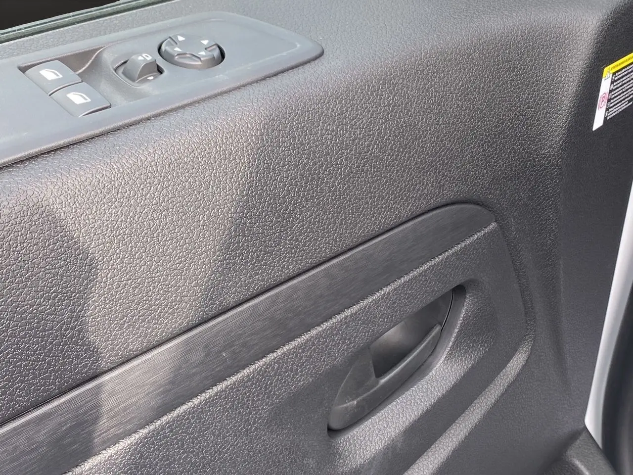 Gros plan sur la porte intérieure côté conducteur de l'Opel Vivaro blanc, avec commandes de vitres et poignée noire.