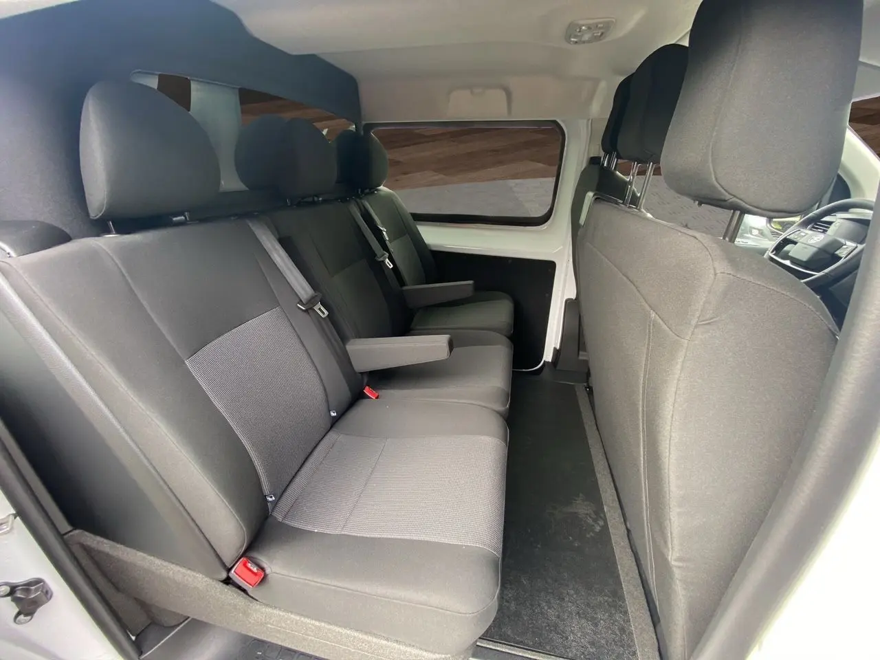 Vue intérieure côté gauche des sièges arrière noirs du fourgon blanc Opel Vivaro 2025 avec accoudoirs et ceintures visibles.