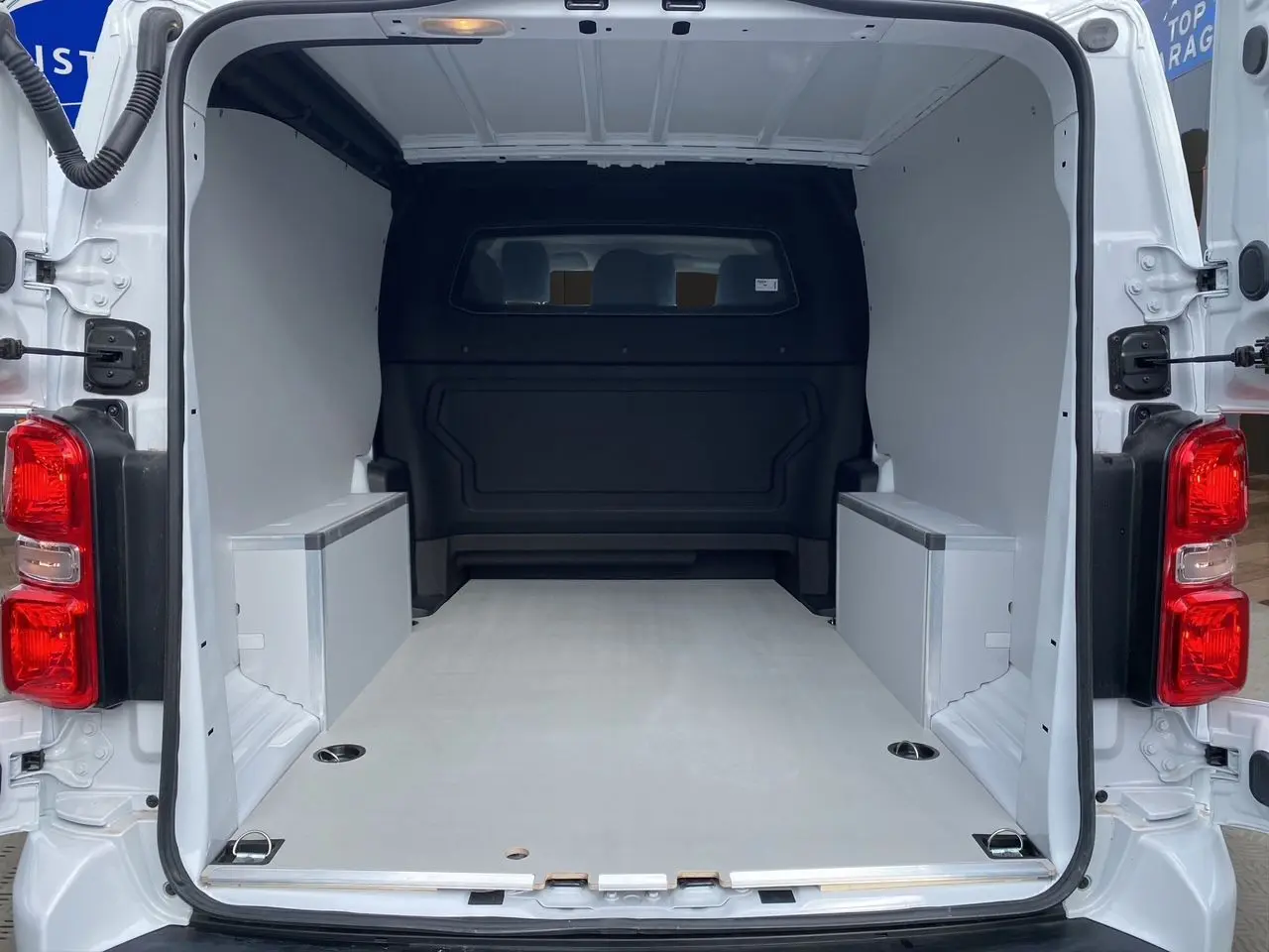 Intérieur arrière du fourgon blanc Opel Vivaro 2025, montrant la zone de chargement vide avec plancher bois antidérapant.