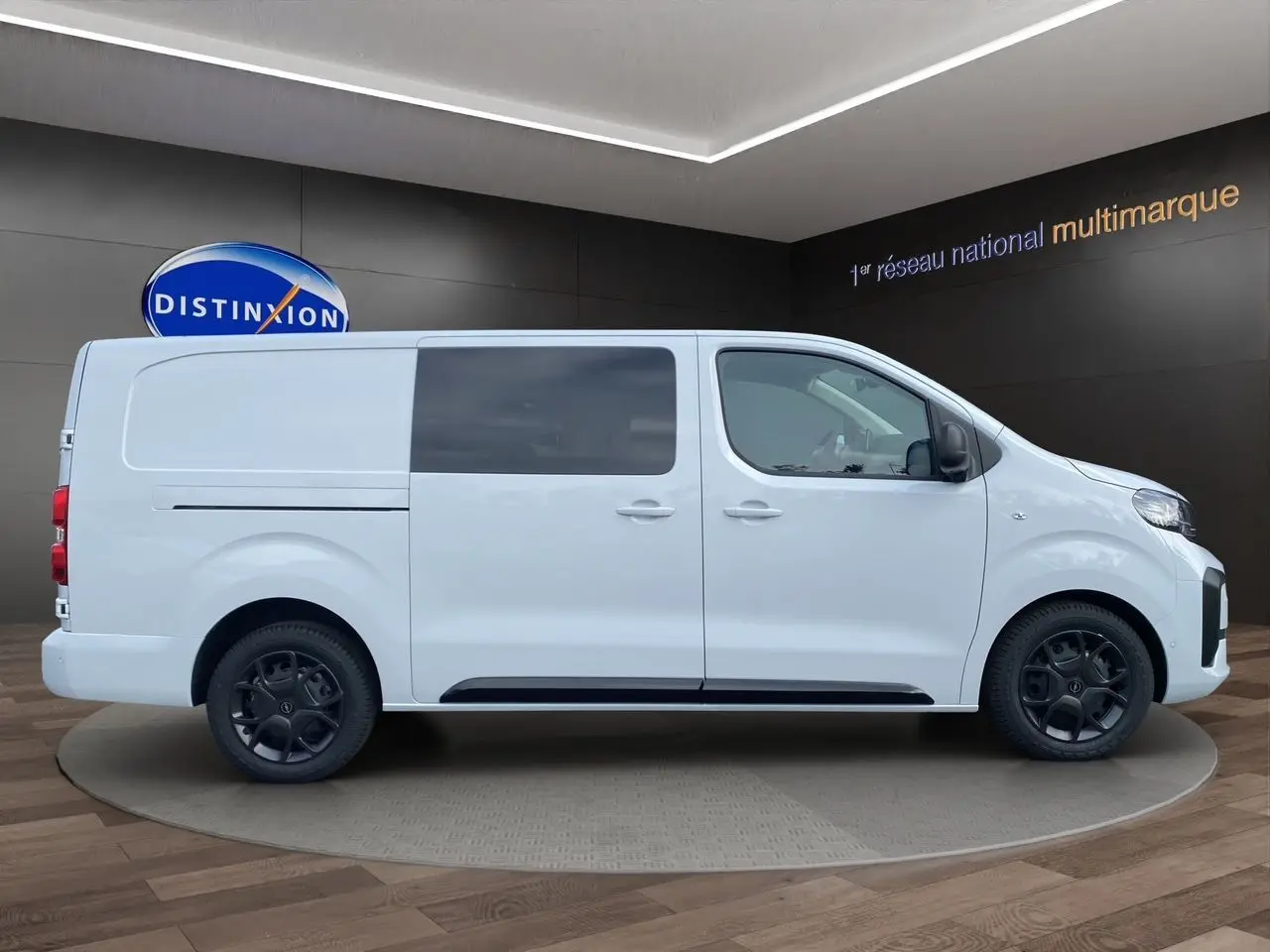 Profil droit d’un Opel Vivaro blanc 2025 avec vitres teintées et jantes noires en présentation showroom.