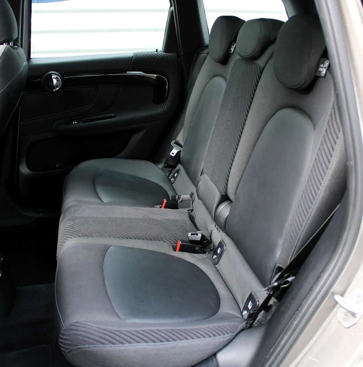 Vue intérieure côté droit des sièges arrière en tissu noir du MINI Countryman II Cooper SE 2018 avec porte ouverte.