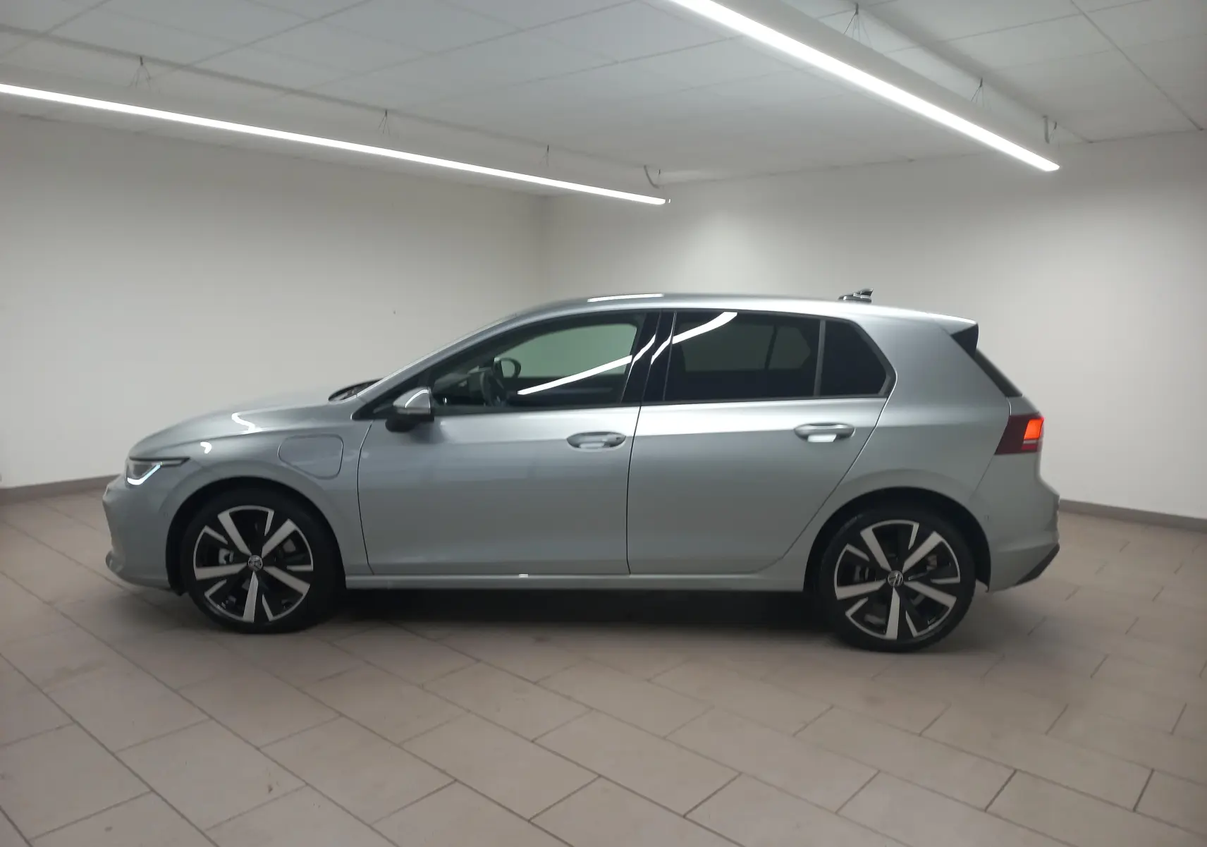 Vue de profil côté gauche d’une Volkswagen Golf 1.5 eHybrid 204 DSG6 en Argent Dolomite avec jantes alliage 18 pouces Catania.