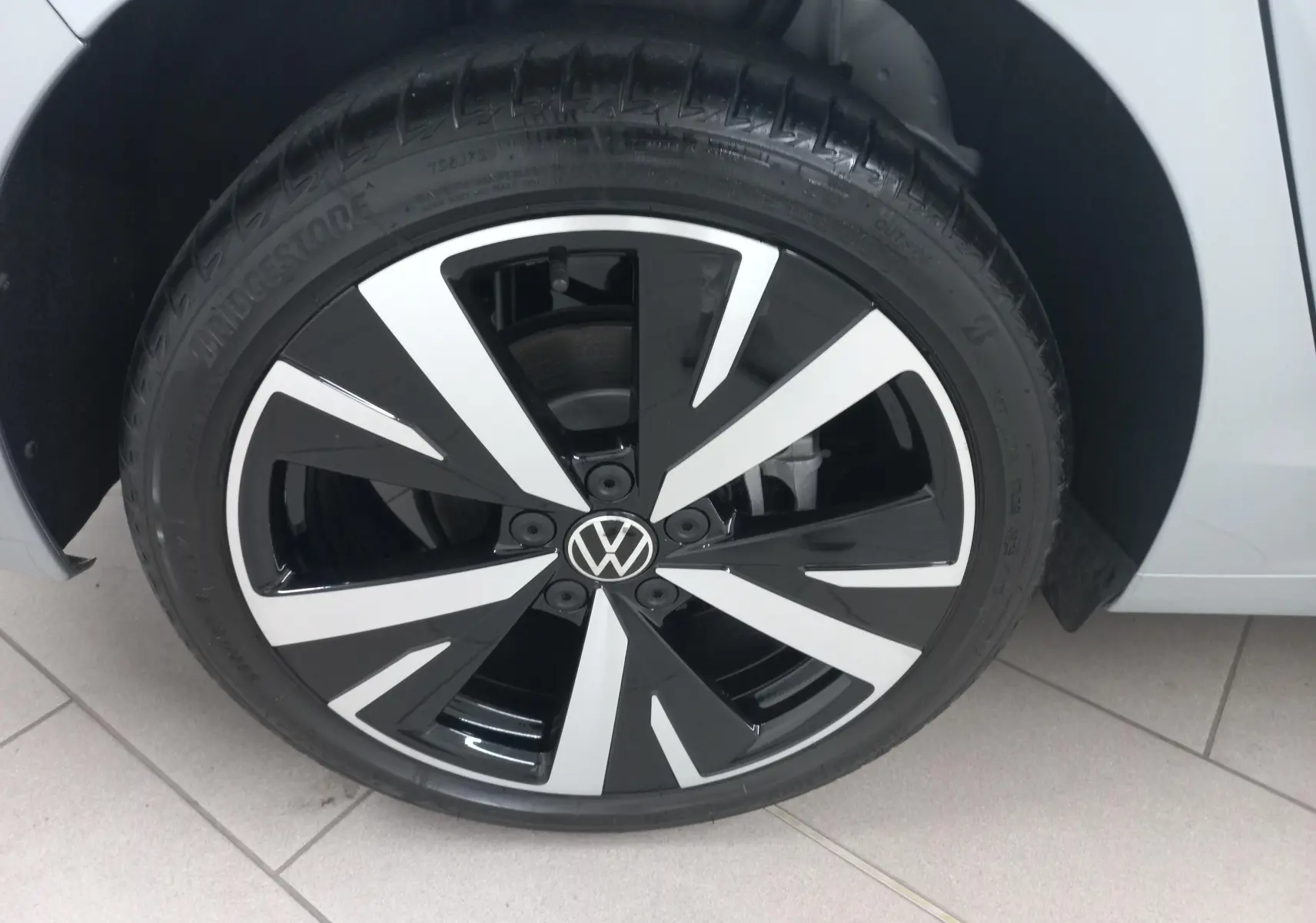 Gros plan sur la jante alliage 18'' Catania bicolore noir et argent d'une Volkswagen Golf 1.5 eHybrid Argent Dolomite.