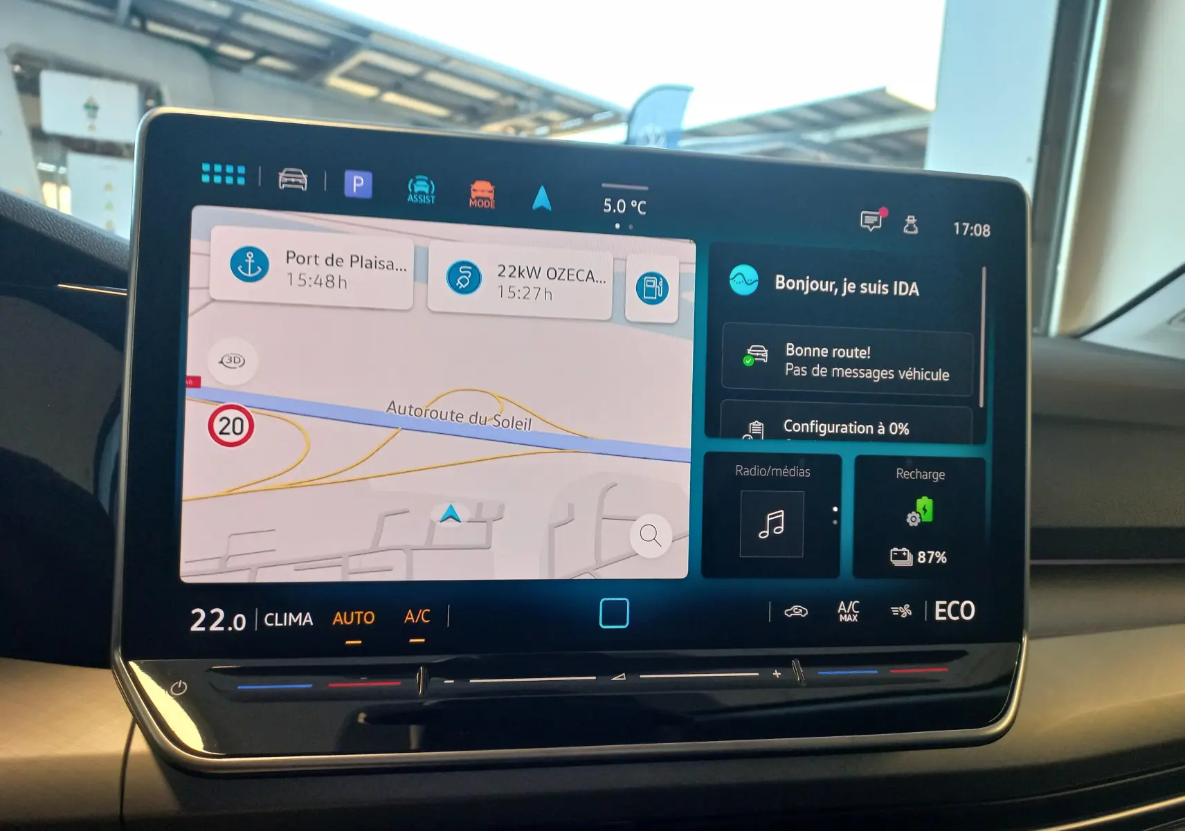 Écran tactile central de la Volkswagen Golf 1.5 eHybrid 2025 affichant navigation, climatiseur et état de recharge à 87%.