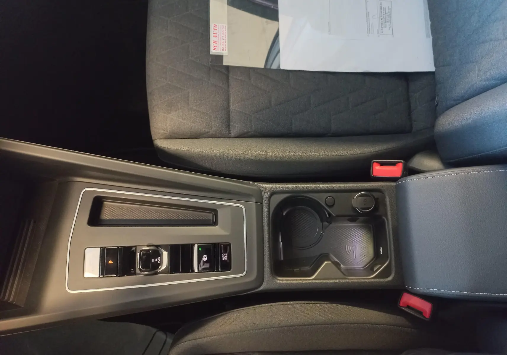 Vue intérieure centrée sur la console centrale de la Volkswagen Golf 1.5 eHybrid 2025 avec sièges tissu gris et commandes de boîte auto.