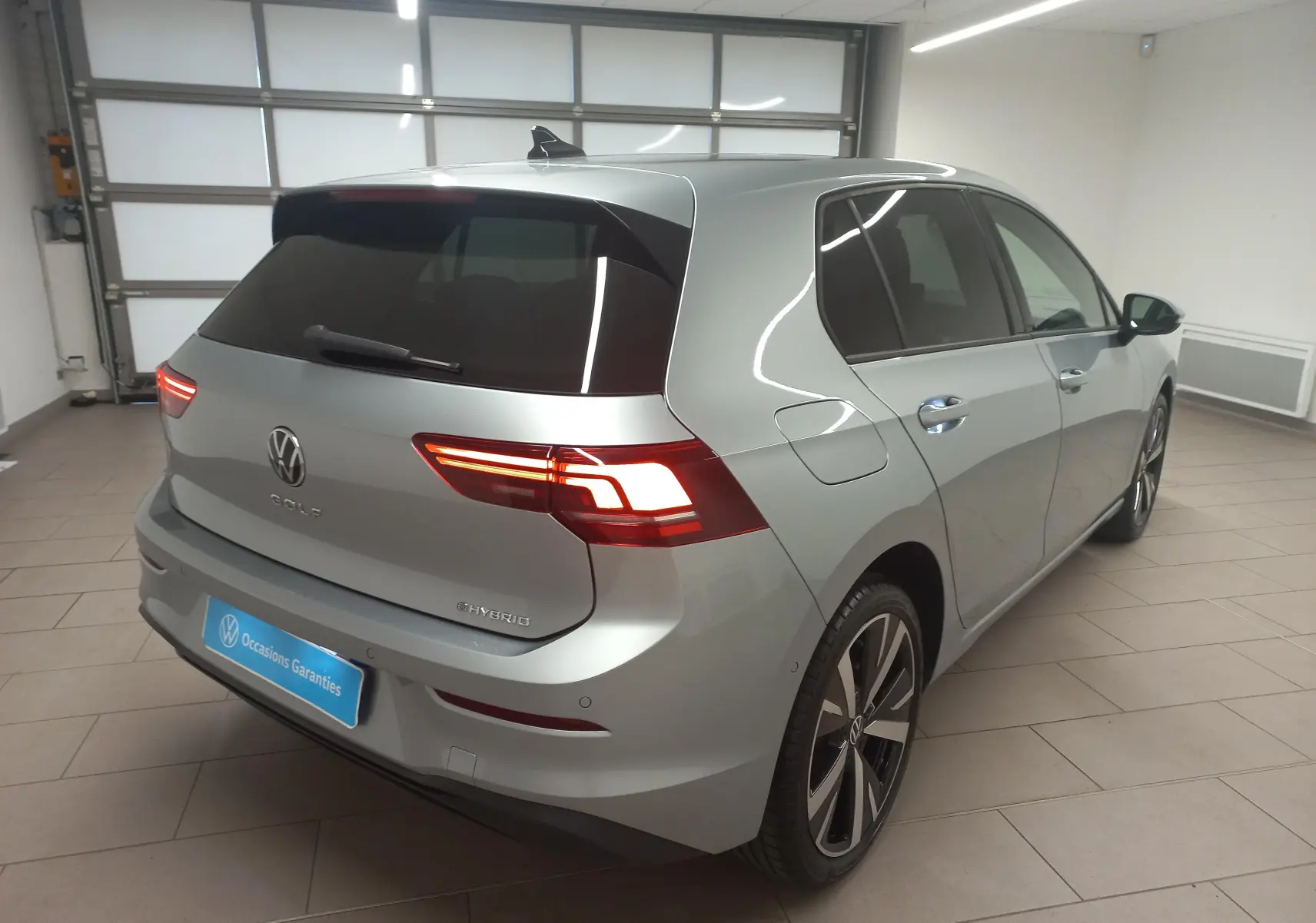 Volkswagen Golf 1.5 eHybrid 2025 en Argent Dolomite, vue 3/4 arrière droit avec jantes alliage 18 pouces Catania.