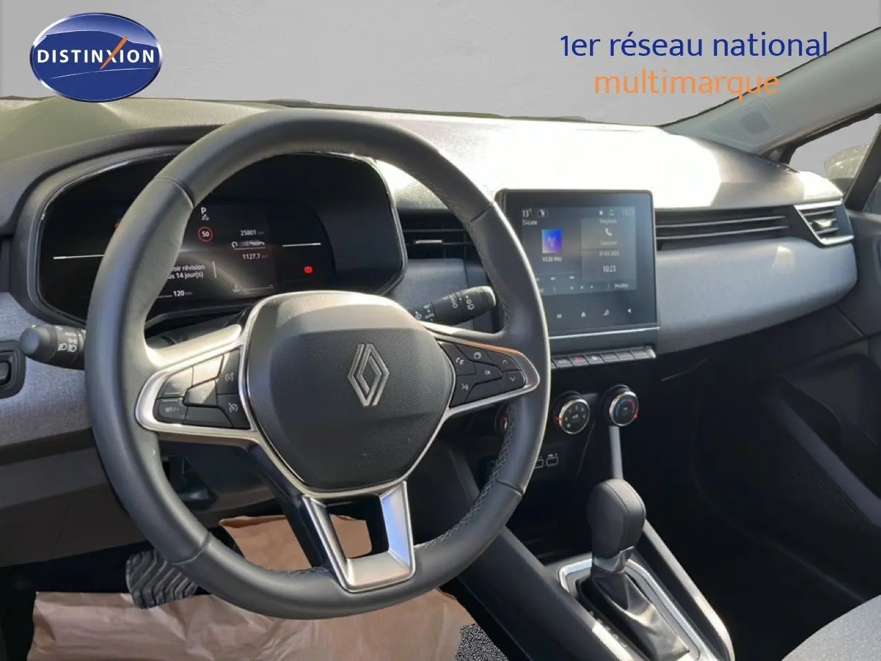 Vue intérieure centrée sur le volant et le tableau de bord de la Renault Clio gris schiste, avec écran tactile et commandes intégrées.