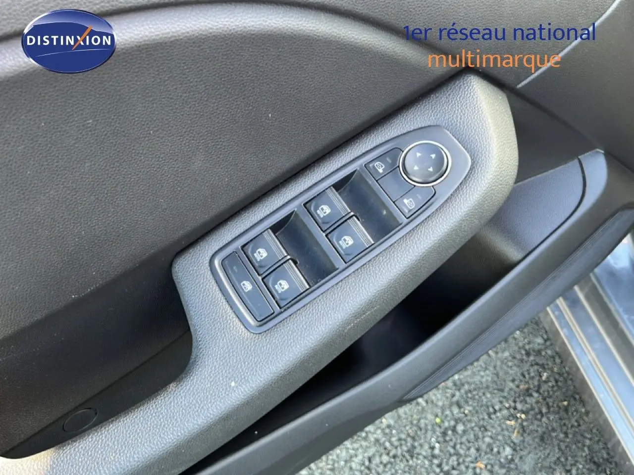 Gros plan sur la commande des vitres électriques côté conducteur de la Renault Clio gris schiste métal, porte ouverte.