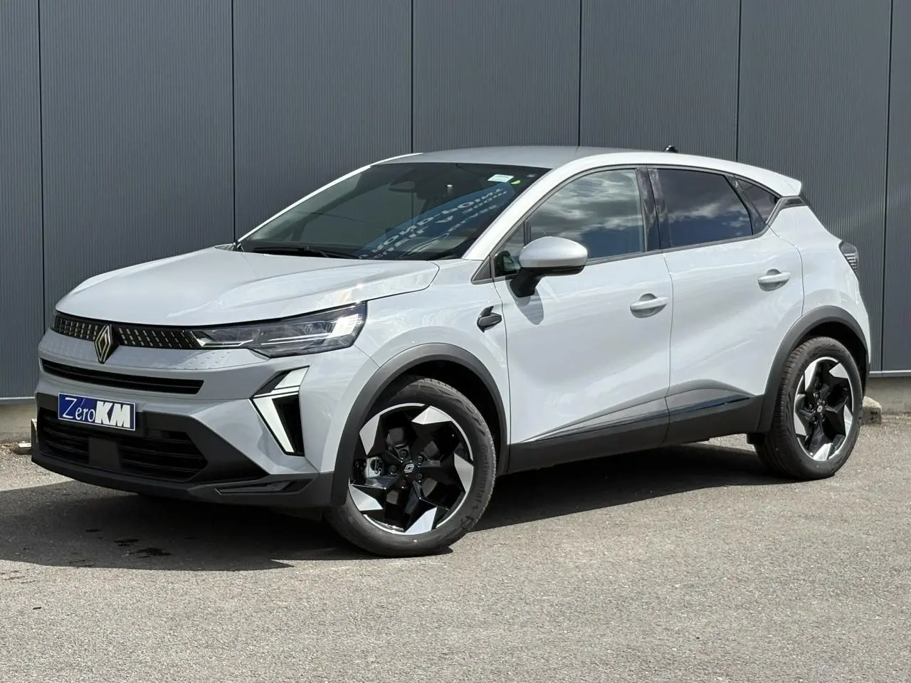Renault Captur 2025 gris Rafale en 3/4 avant droit avec jantes noires et toit gris Highland visible