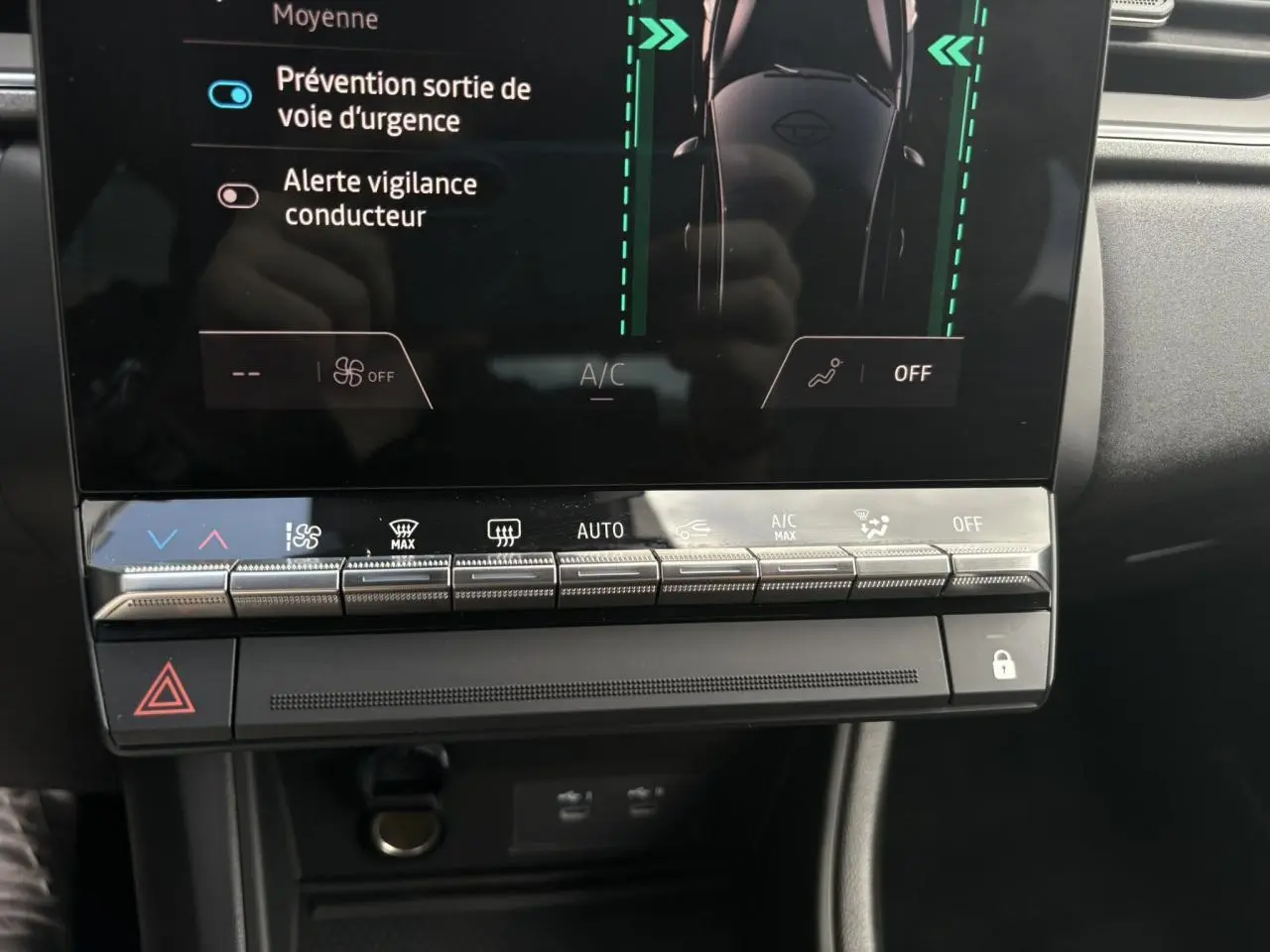 Vue rapprochée de la console centrale du Renault Captur gris Rafale, avec commandes climatisation et écran tactile affichant les aides à la conduite.
