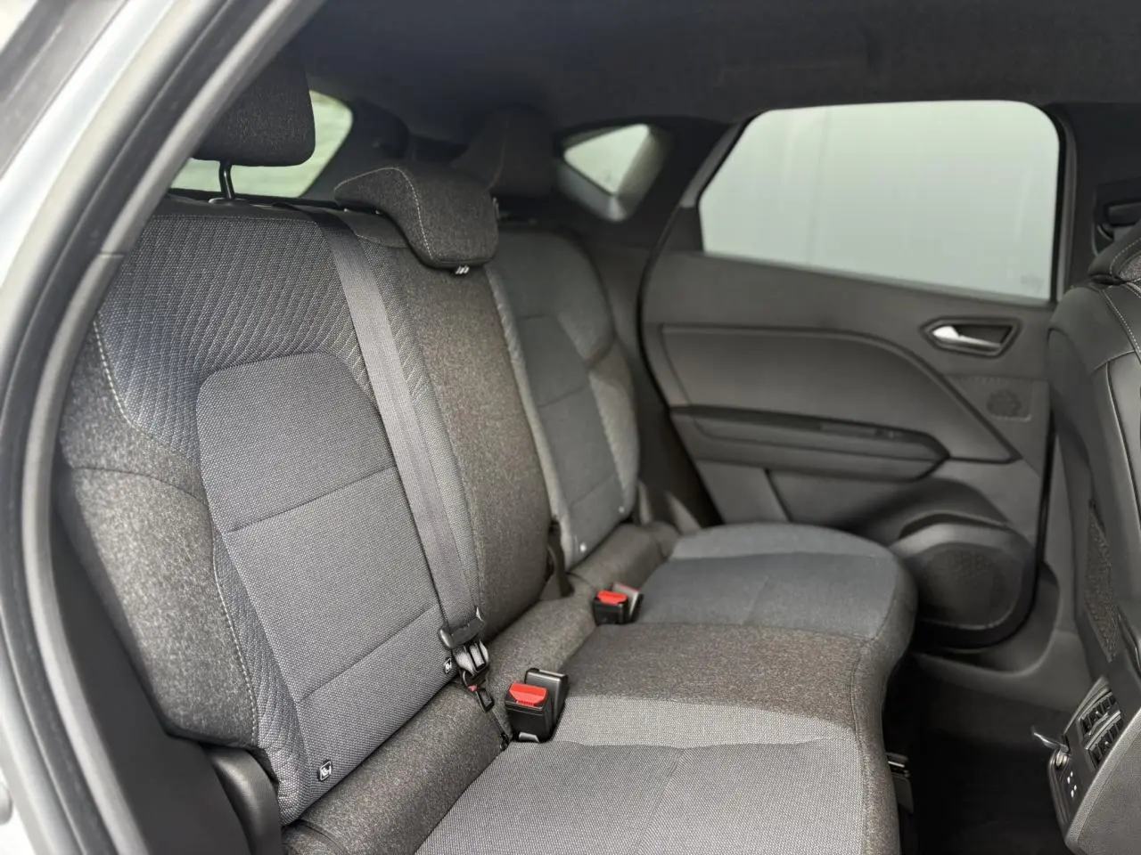 Vue intérieure côté droit des sièges arrière gris foncé du Renault Captur 2025 avec ceinture de sécurité et appuis-tête.