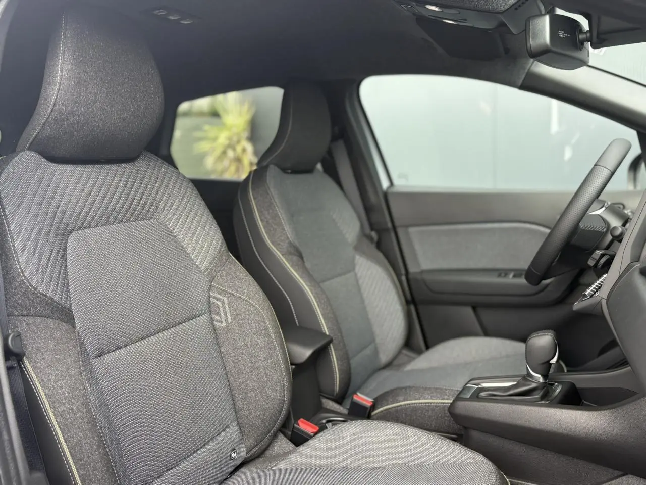 Intérieur Renault Captur 2025, vue côté gauche sur sièges gris texturés et console centrale avec levier de vitesse.