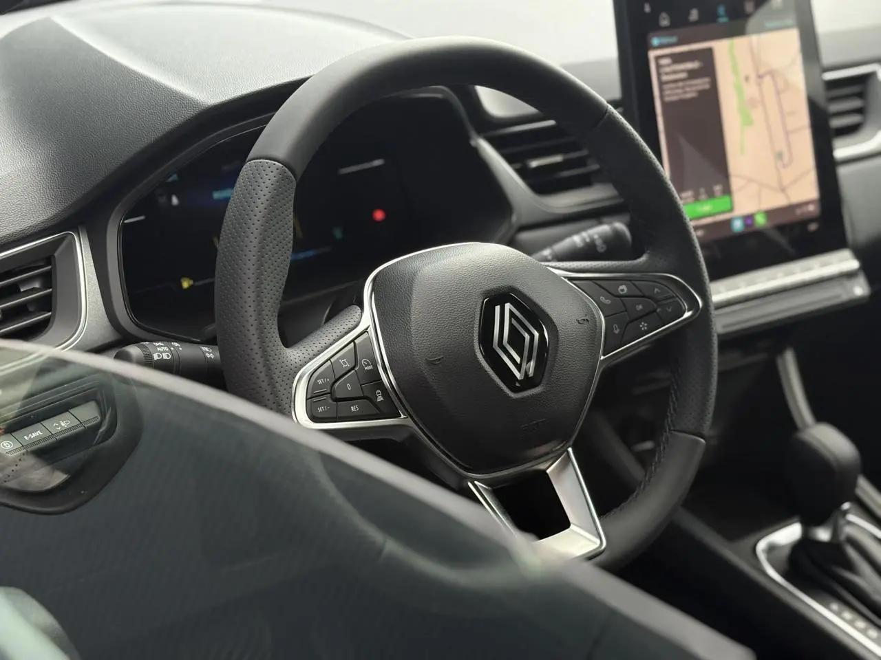 Vue rapprochée du volant noir perforé et du tableau de bord numérique du Renault Captur Gris Rafale 2025.