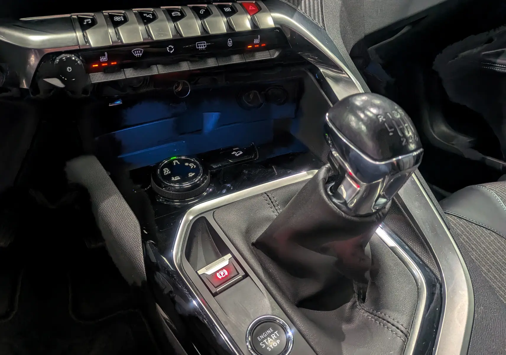 Gros plan sur la console centrale du Peugeot 3008 noir Perla, mettant en valeur le levier de vitesses manuel et les commandes tactiles.