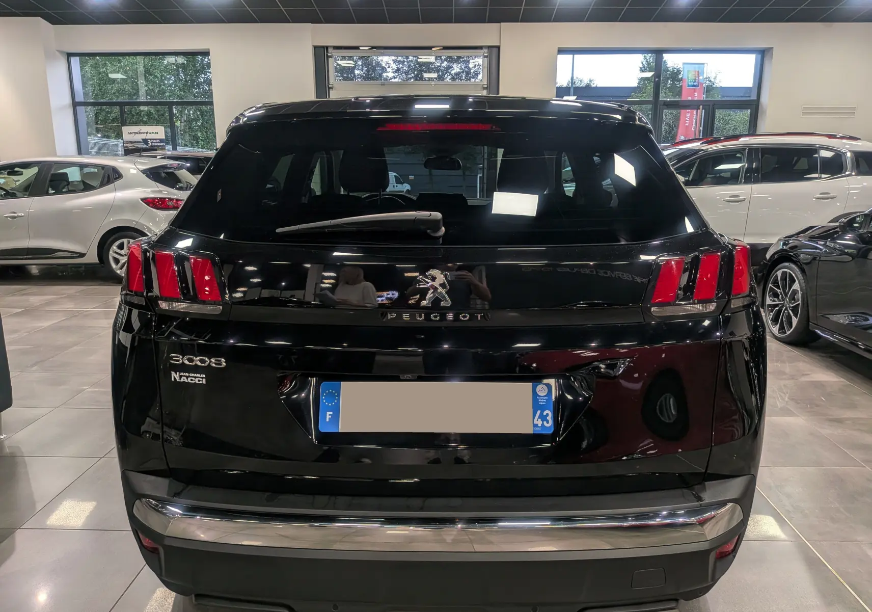 Vue arrière d'un Peugeot 3008 noir Perla 2022 dans un showroom, avec feux arrière distinctifs à trois griffes rouges.