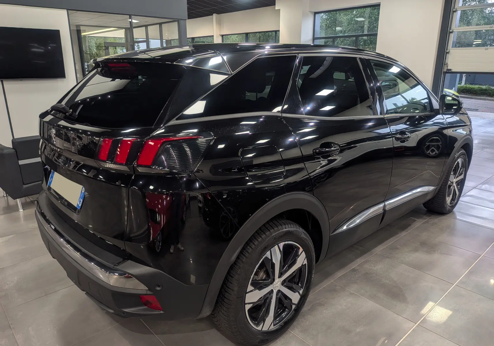 Vue 3/4 arrière droite du Peugeot 3008 noir Perla 2022 en showroom, avec feux arrière à triple griffes rouges distinctifs.