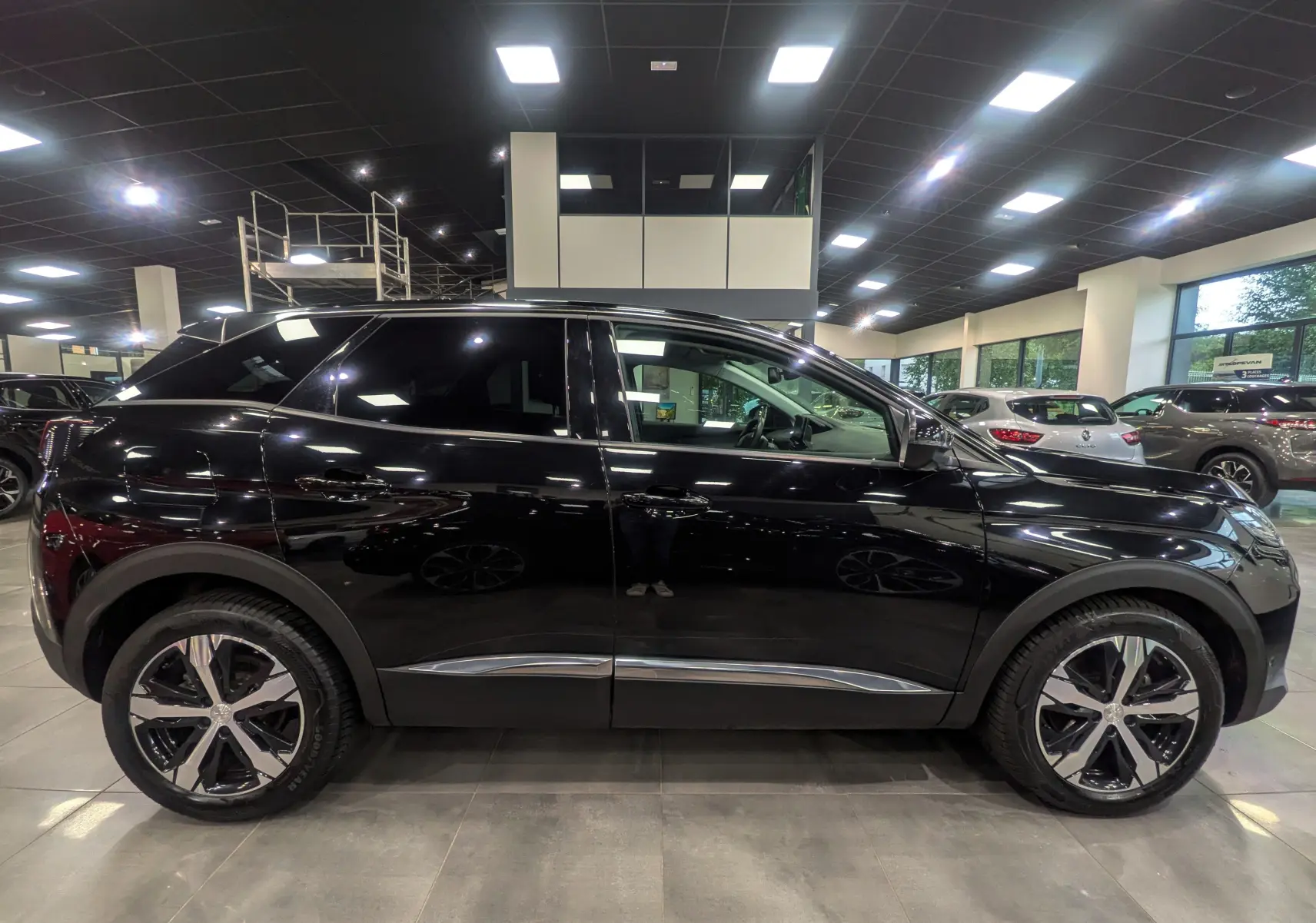 Profil latéral droit d'un Peugeot 3008 BlueHDi 130 Allure noir Perla avec jantes alliage bicolores en showroom.
