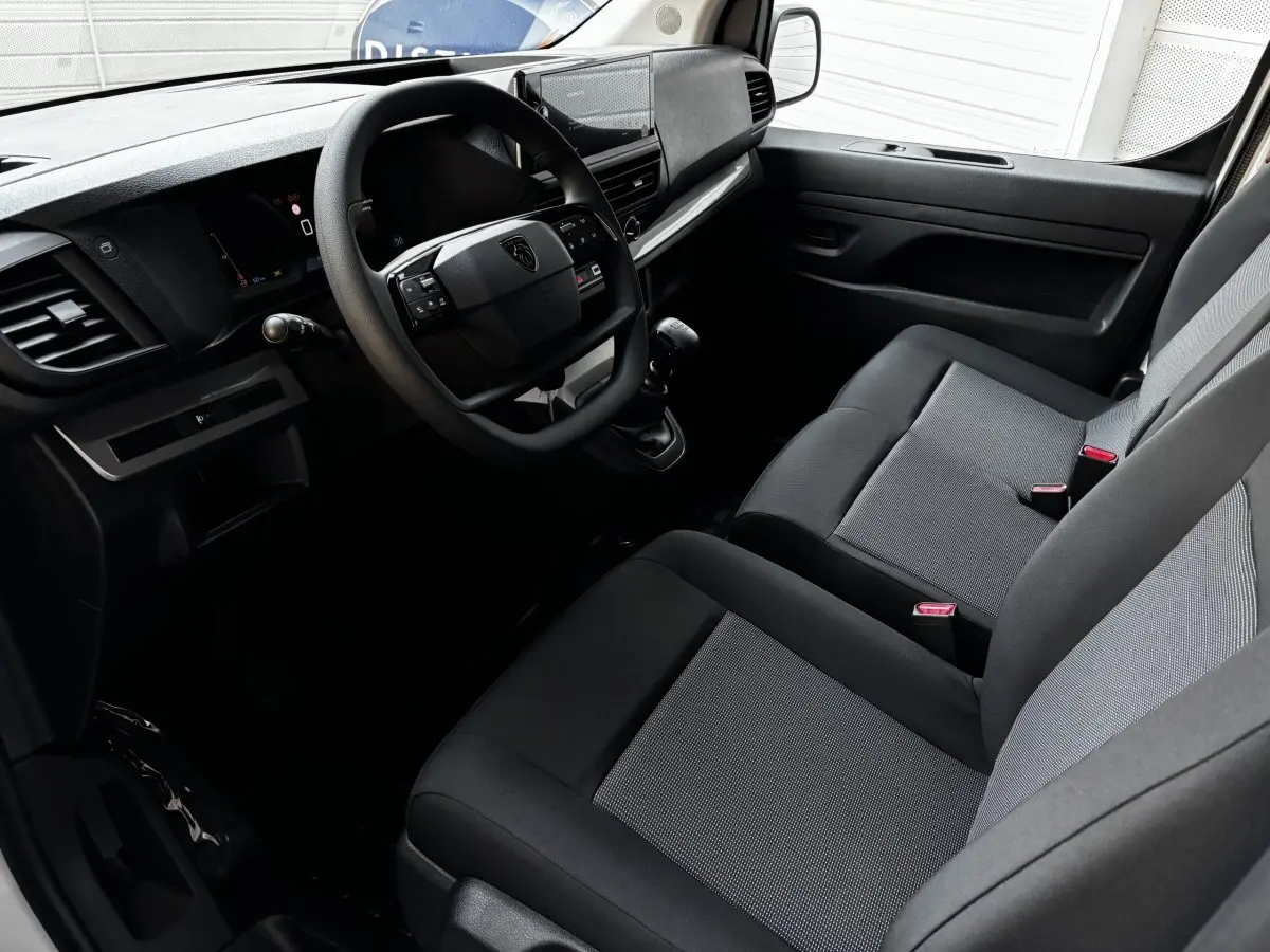 Intérieur côté conducteur du Peugeot Expert Fourgon 2025, montrant tableau de bord moderne et sièges tissu gris et noir.