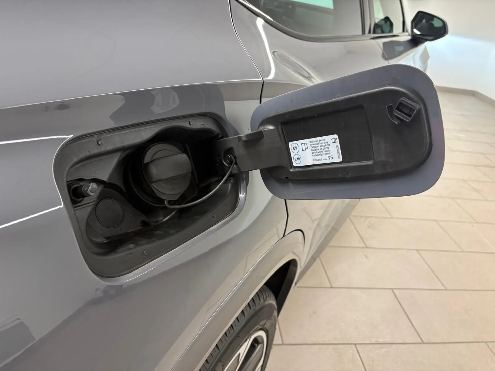 Gros plan sur la trappe à carburant ouverte côté gauche du CUPRA Formentor gris Graphène, montrant le bouchon essence.