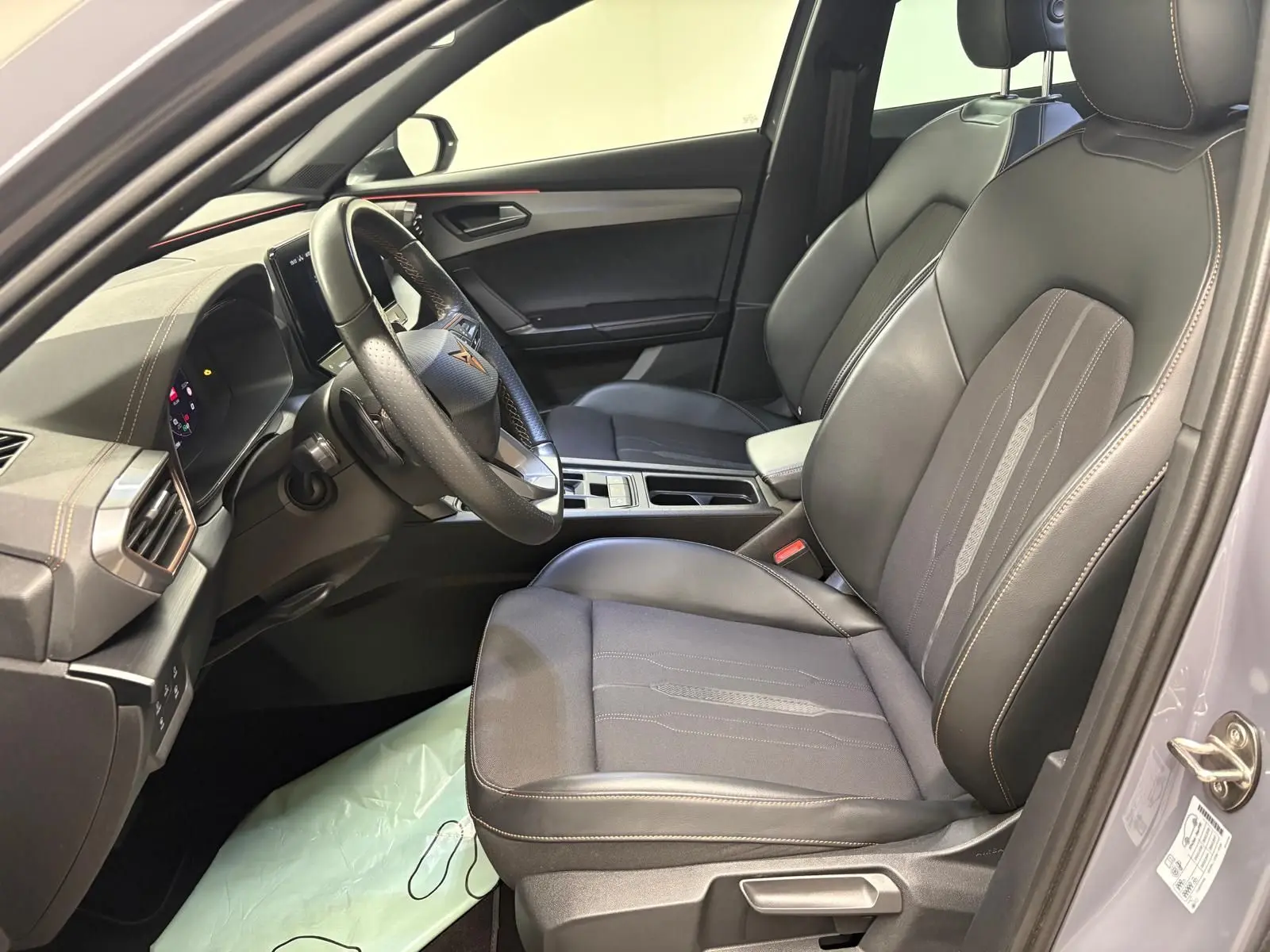 Vue intérieure côté conducteur de la CUPRA Formentor gris Graphène, sièges avant en cuir avec surpiqûres contrastées et volant multifonction.