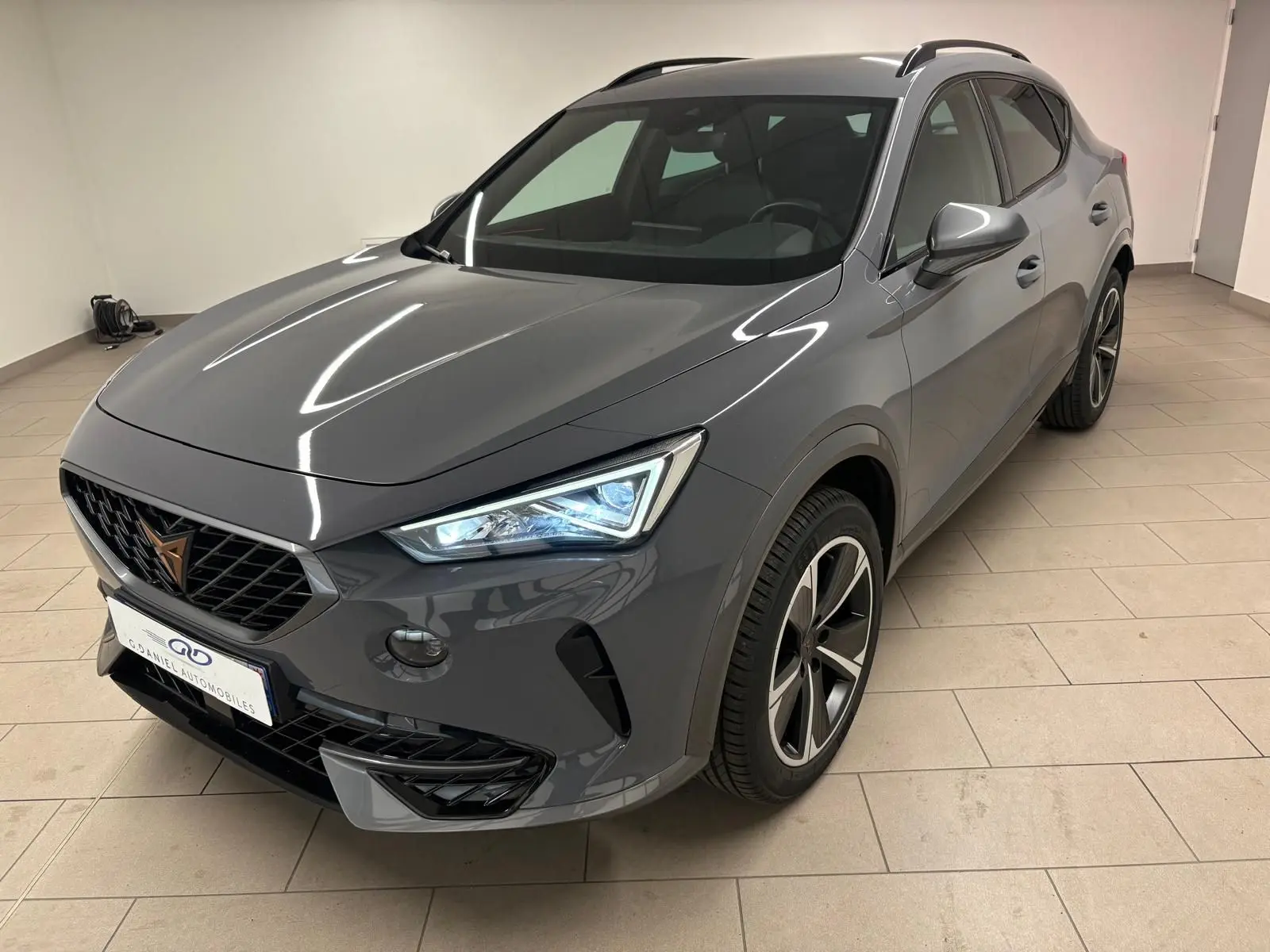 Vue 3/4 avant droite du CUPRA Formentor gris Graphène avec jantes alliage 18'' et phares LED allumés.