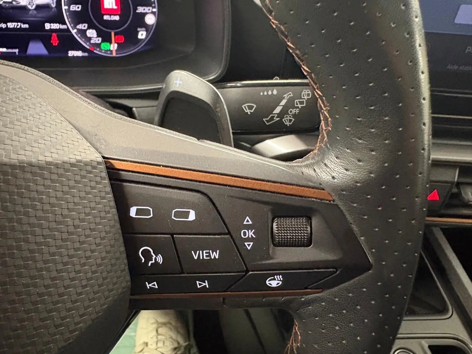 Gros plan sur le volant perforé avec commandes intégrées du CUPRA Formentor gris Graphène, tableau de bord numérique en arrière-plan.