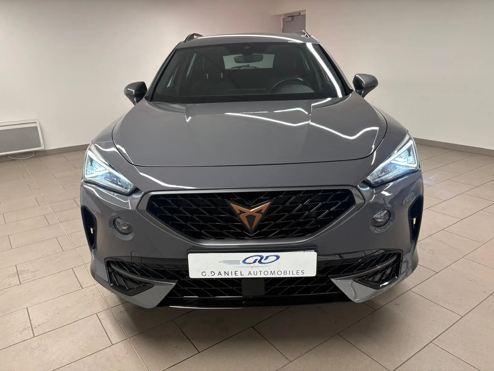 Vue avant d'une CUPRA Formentor 1.5 TSI 2022 en gris Graphène avec calandre noire et feux LED allumés.