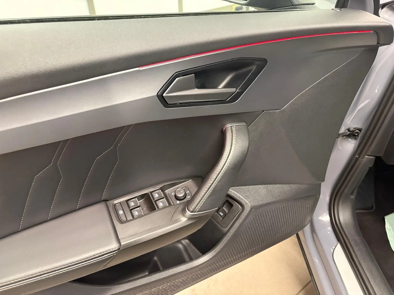 Vue rapprochée de la porte avant gauche d'une CUPRA Formentor gris graphène avec surpiqûres et commandes électriques.