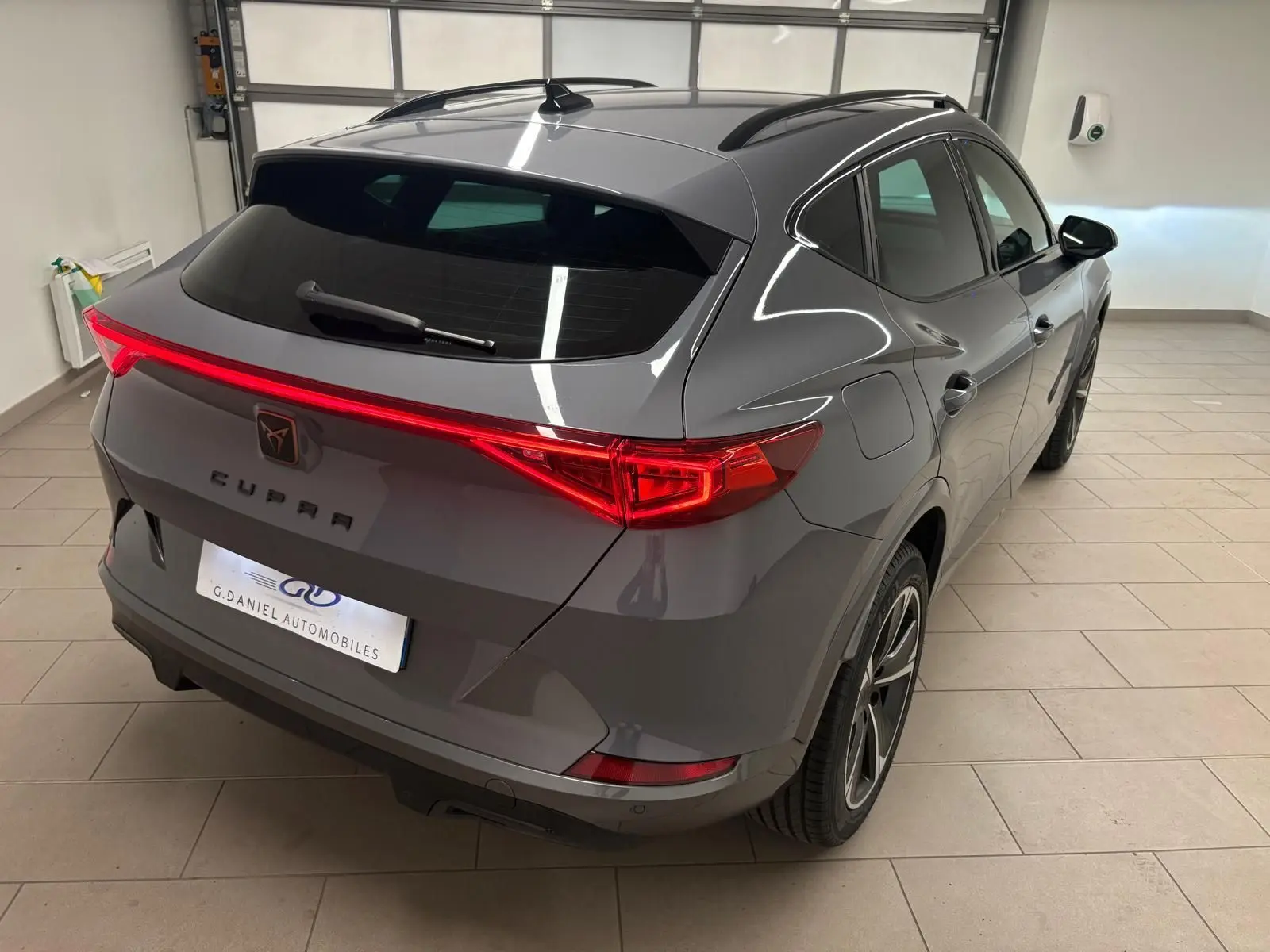 Vue 3/4 arrière droite du CUPRA Formentor gris Graphène avec feux arrière allumés et jantes 18 pouces en alliage.