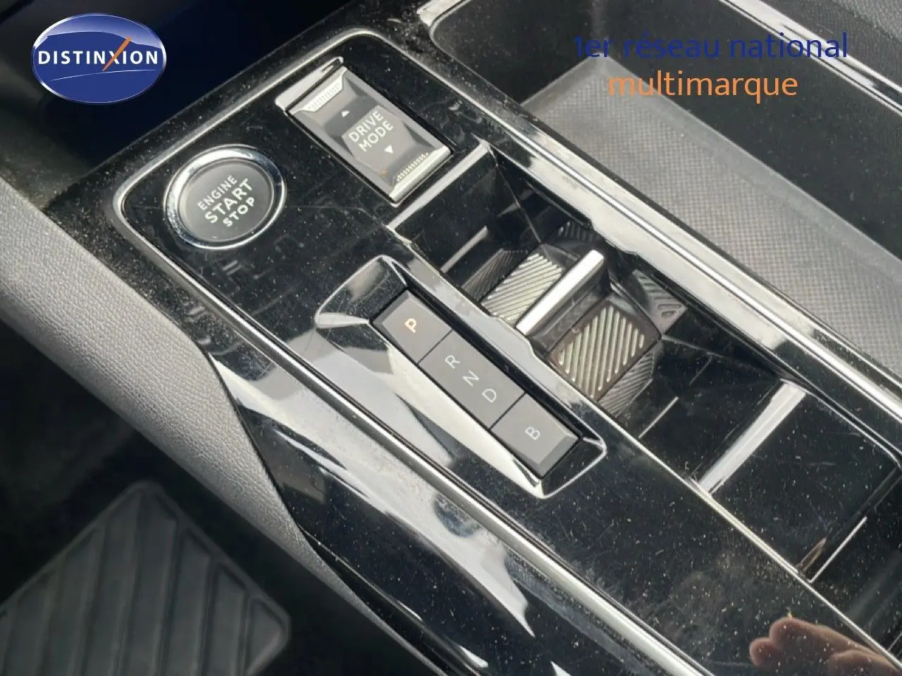 Gros plan sur la console centrale noire brillante du Peugeot 3008 hybride rechargeable avec boutons de démarrage et sélection de mode de conduite.