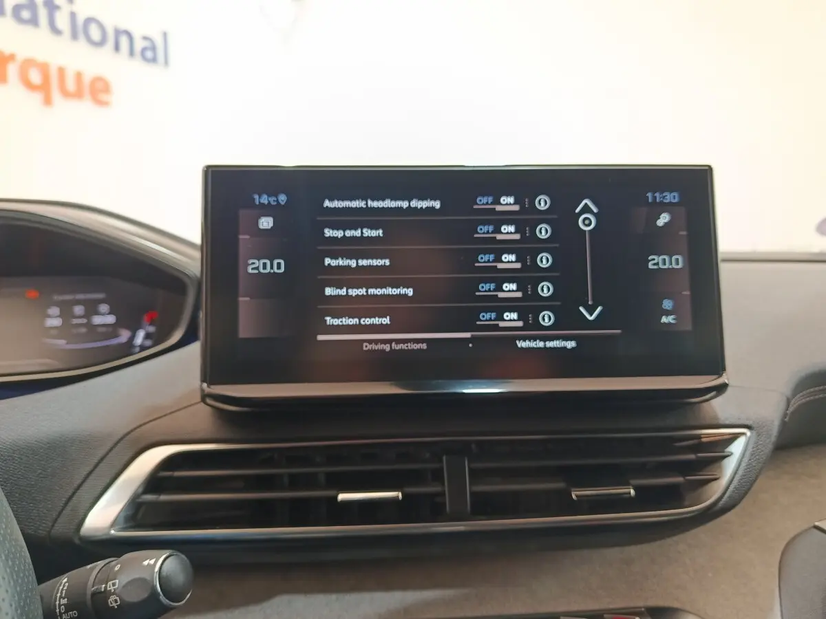 Vue intérieure du tableau de bord central du Peugeot 5008 bleu 2023, avec écran tactile affichant les réglages de conduite.