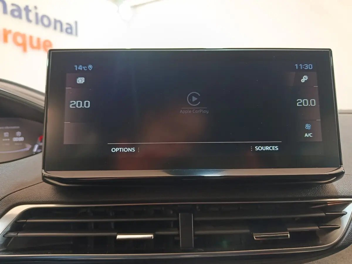 Écran tactile central du tableau de bord du Peugeot 5008 GT 2023 affichant Apple CarPlay et réglages climatisation.