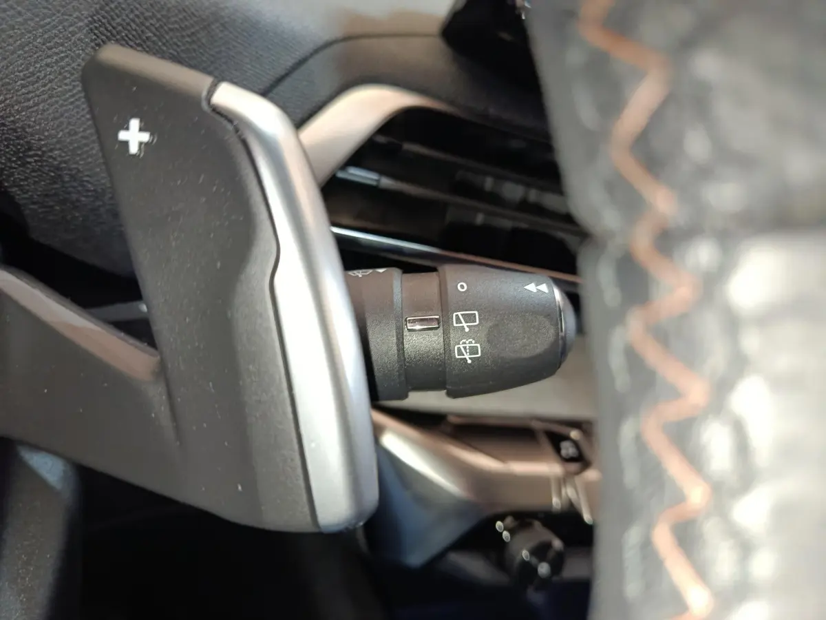 Gros plan sur la palette de changement de vitesse + côté gauche du volant cuir du Peugeot 5008 GT 2023, intérieur noir.
