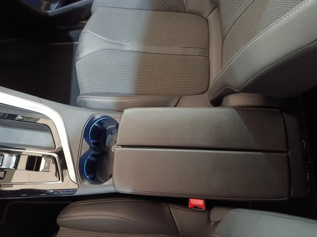 Vue rapprochée de l'accoudoir central noir et des sièges en cuir gris foncé du Peugeot 5008 GT 2023.