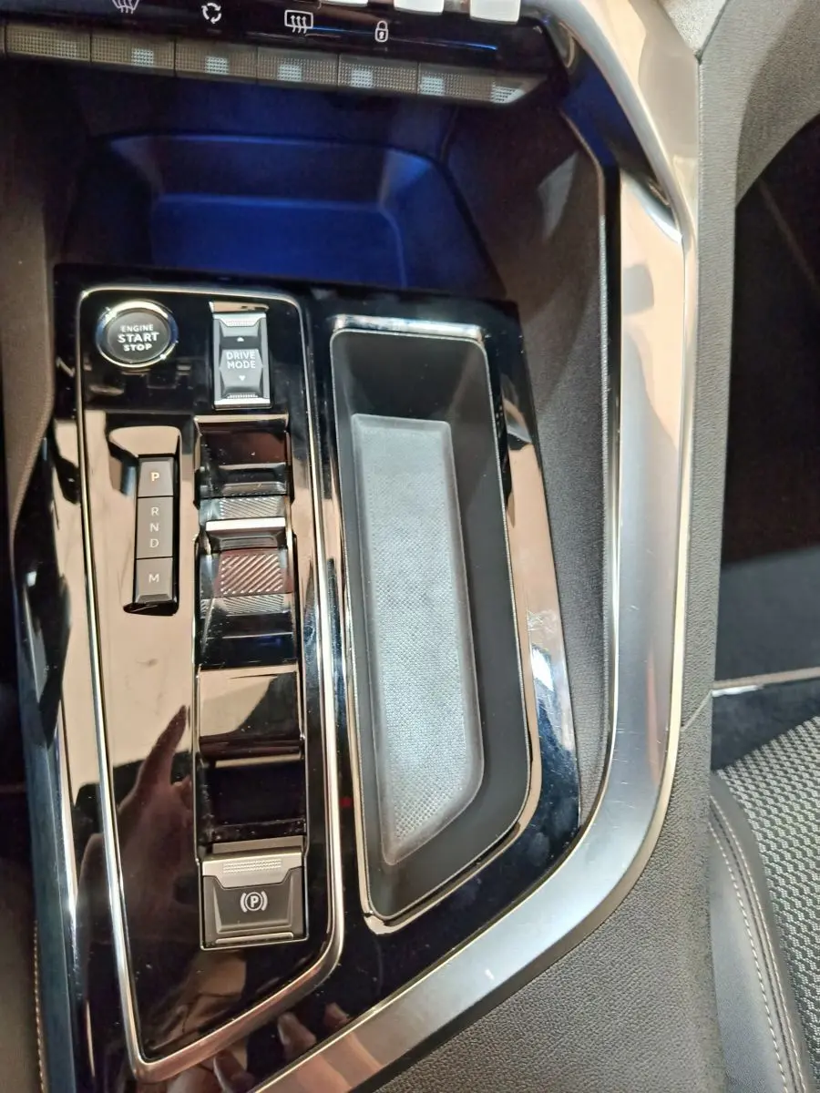 Gros plan sur la console centrale noire brillante du Peugeot 5008 avec bouton démarrage et sélecteur de mode de conduite.