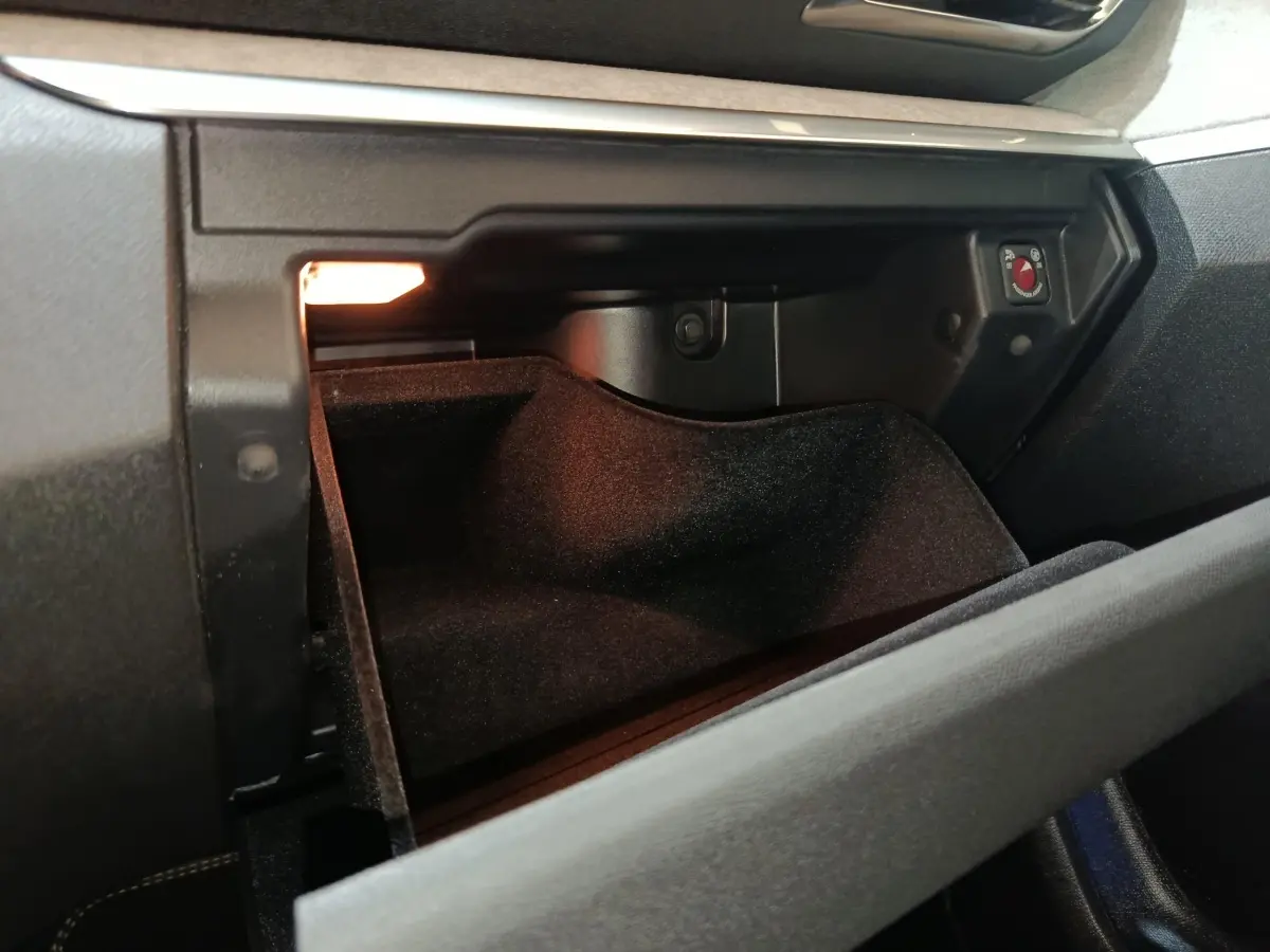 Vue rapprochée de la boîte à gants ouverte du Peugeot 5008 GT 2023, intérieur noir avec éclairage intérieur.
