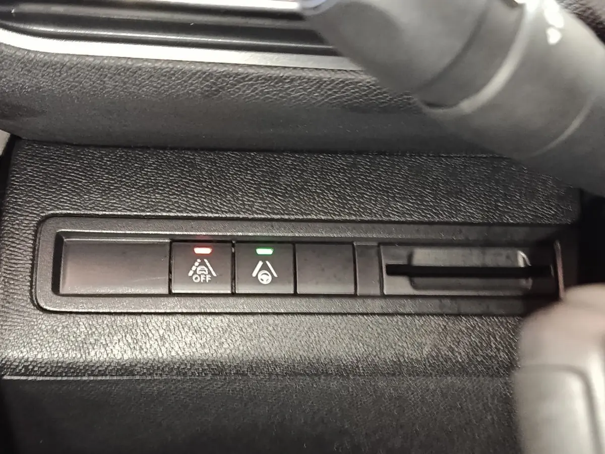 Gros plan sur les boutons d'aide à la conduite du Peugeot 5008 GT 2023, avec voyants rouge et vert allumés.
