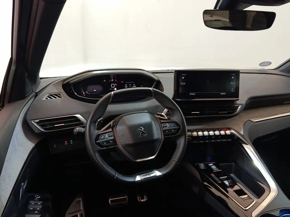 Vue intérieure du poste de conduite du Peugeot 5008 GT 2023, avec volant cuir, écran tactile central et combiné numérique.