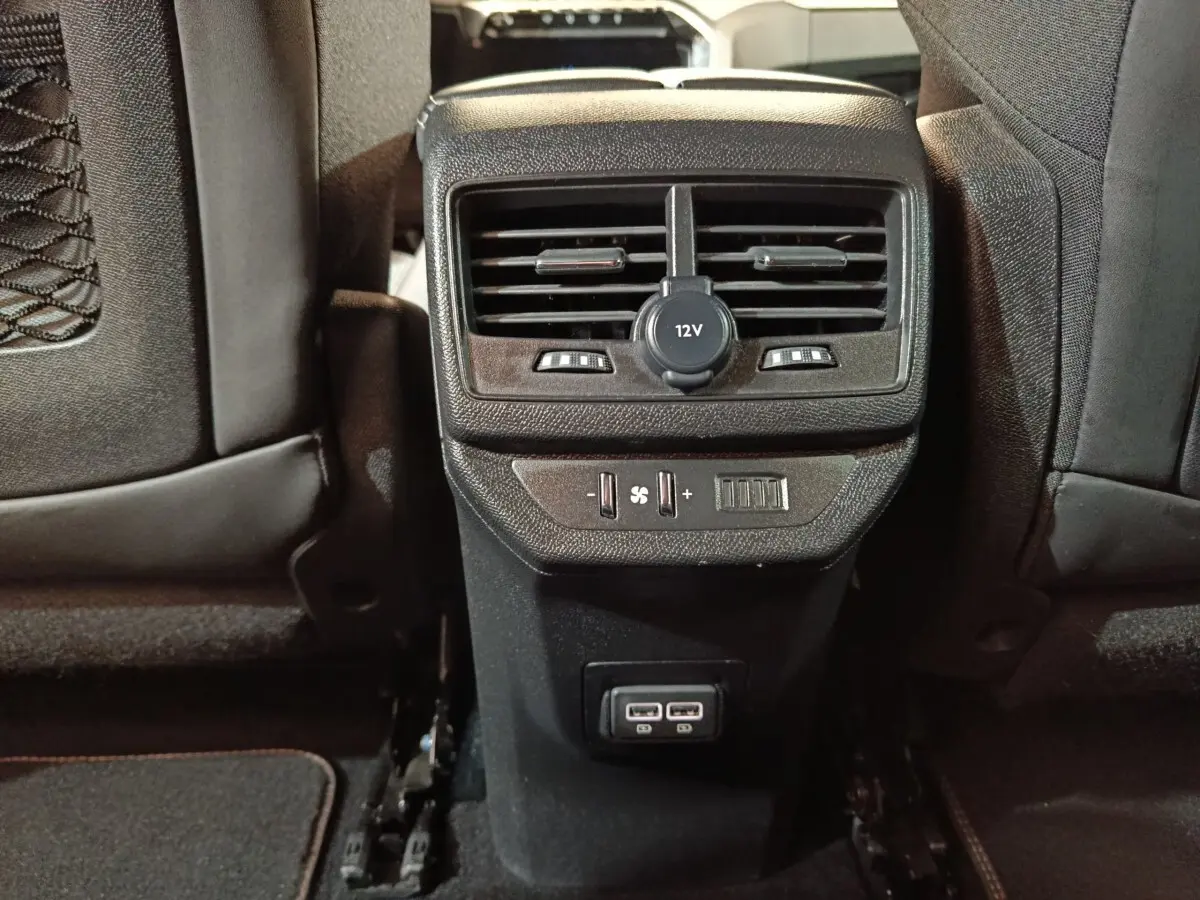 Vue rapprochée de la console arrière noire du Peugeot 5008 GT 2023 avec prises USB et commandes de ventilation.