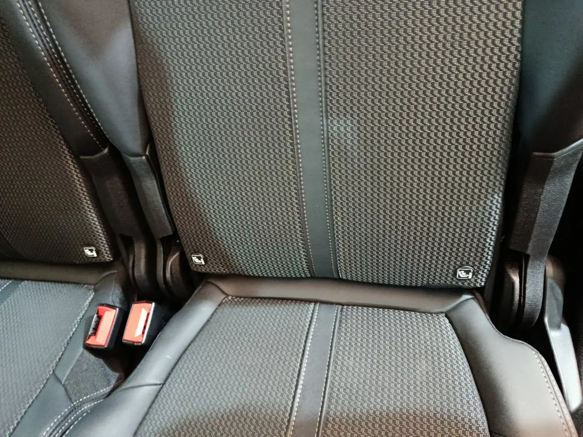 Gros plan sur les sièges arrière noirs du Peugeot 5008 2023 avec ceintures rouges et logo Isofix visible.