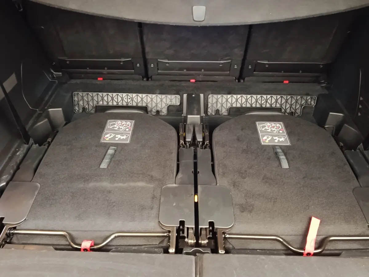Vue rapprochée du coffre arrière du Peugeot 5008 bleu 2023 avec sièges rabattus et espace de rangement plat.