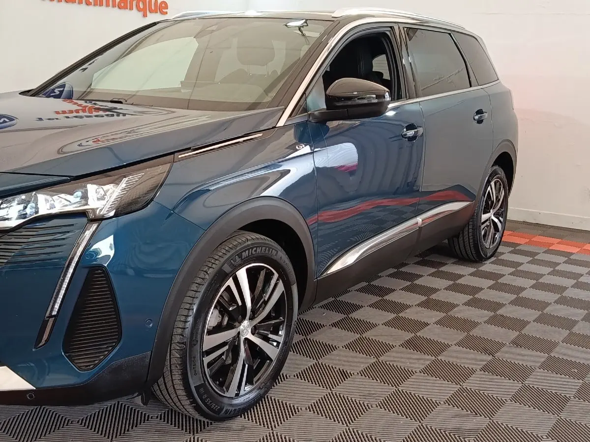 Vue 3/4 avant droit du Peugeot 5008 bleu 2023 avec jantes alliage et feux LED distinctifs.