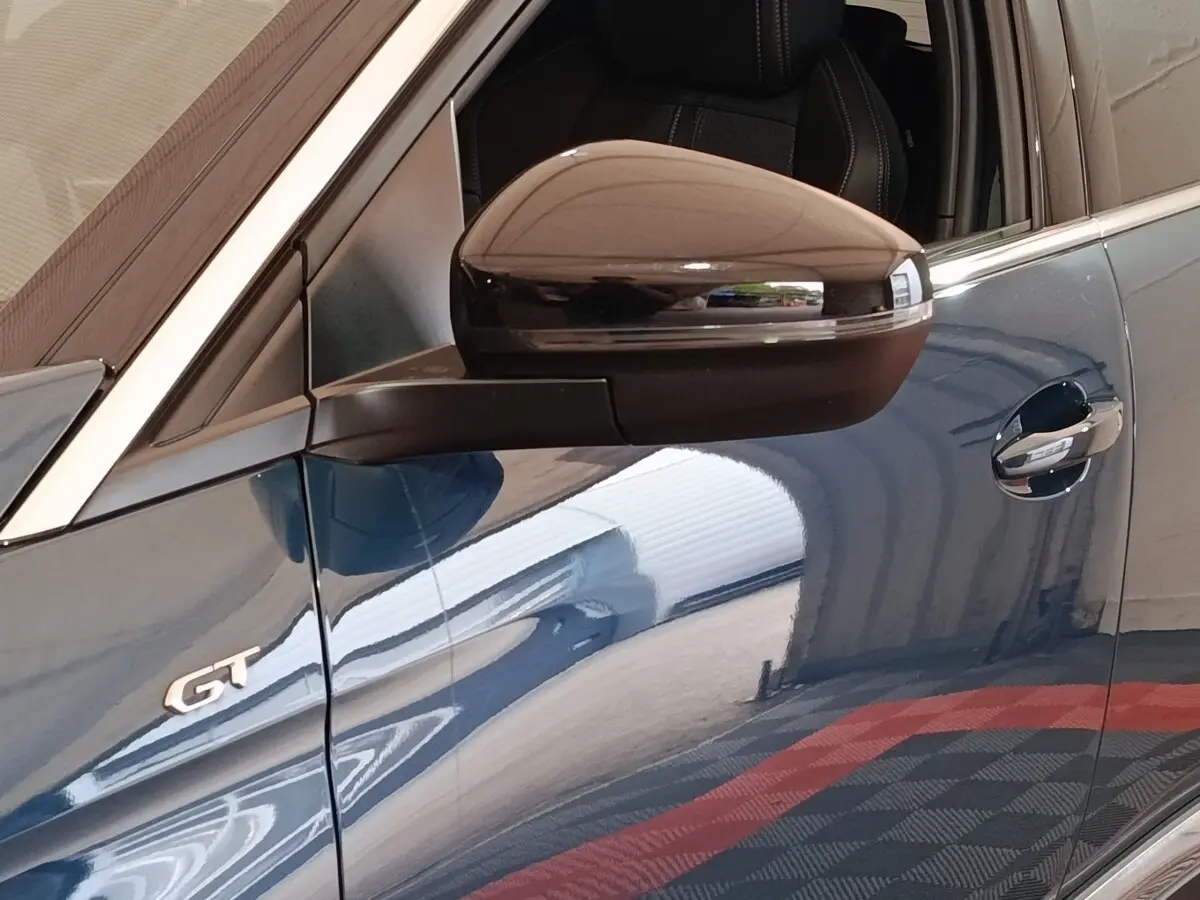 Gros plan sur la porte côté gauche d’un Peugeot 5008 GT bleu avec rétroviseur noir et badge GT visible.