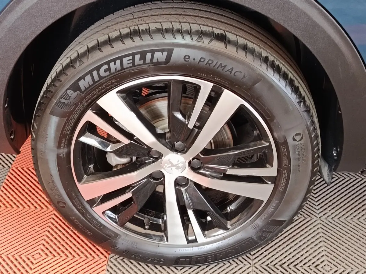 Gros plan sur la roue avant droite du Peugeot 5008 bleu, mettant en valeur la jante alliage bicolore et le pneu Michelin.